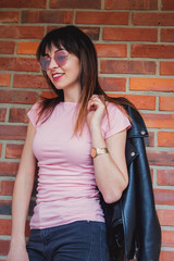 Young brunet girl with sunglasses on brick wall background