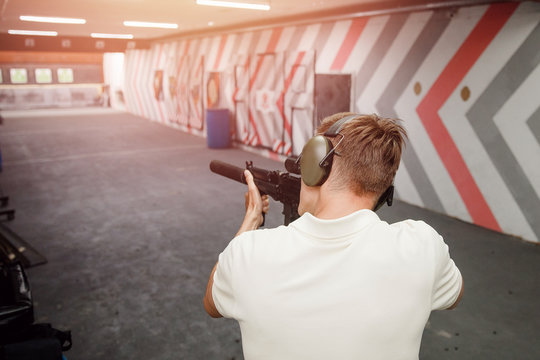 Man shoots pistol in noise protection headphones. Shooting range gun