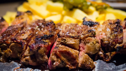 Close-up detail of a beef rib grilled with fried potatoes