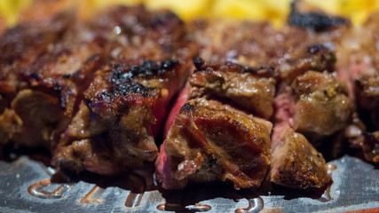 Close-up detail of a beef rib grilled with fried potatoes