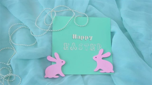 Easter holiday concept with cute handmade card and pink rabbits on turquoise background