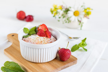 Homemade cheesecake with strawberry and mint on a wooden cutting board