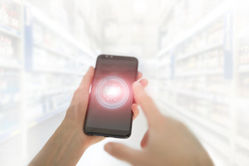 Shopping basket on a mobile phone screen. Woman Hand holding mobile phone on Supermarket blur background