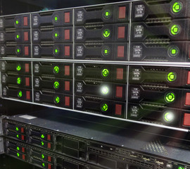 Many powerful servers running in the data center server room. Disk storage array. Image has noise.