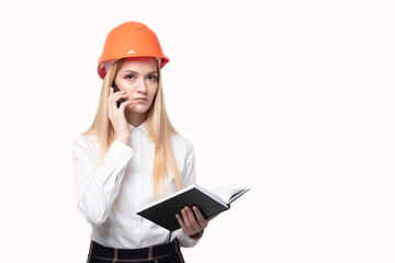 Girl engineer in a protective helmet talking on the phone