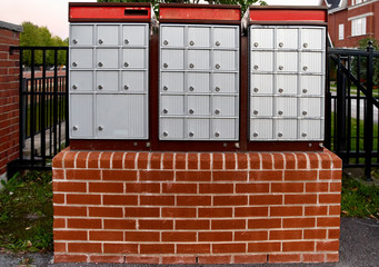 Community mailboxes. Three groups. Overcast sky above. Slot for sending mail. Closeup view. Room for text above.