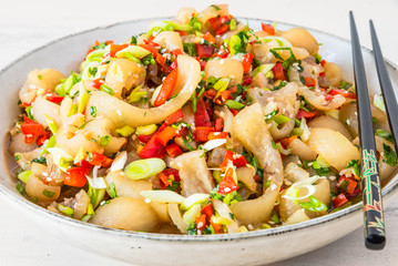 Traditional Asian appetizer - stir-fry spicy sliced pork skin with spices on a plate, close-up, rustic wooden background. Chinese and Thai dish.