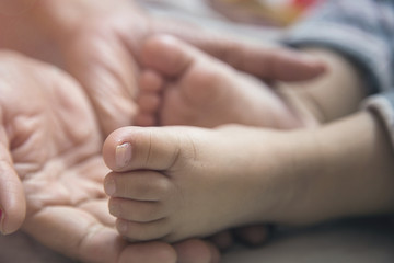 Close up Mother Holding Feet of infant Baby in Her Hand.