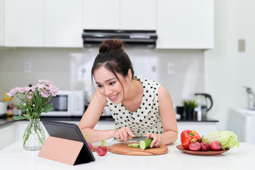 woman using tablet while making a healthy salad at the kitchen