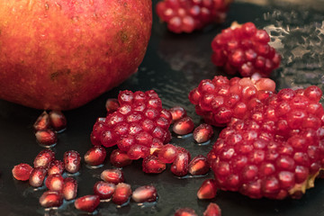 Fresh colorful pomegranates fruits close up on black table	