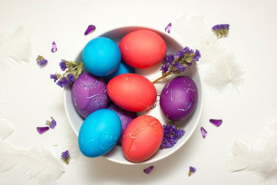 Top shot of Happy Easter decoration with colored chicken eggs in bowl on white background with free space for text