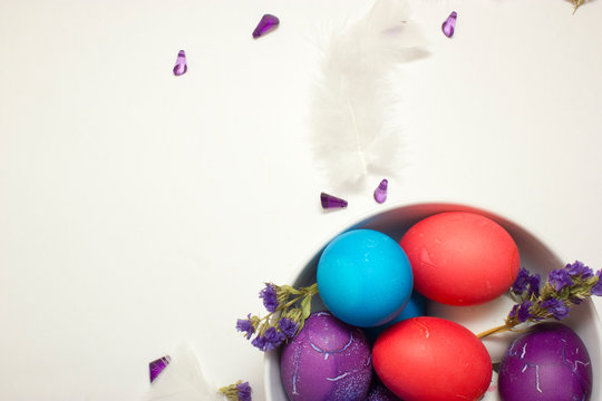 Top shot of Happy Easter decoration with colored chicken eggs in bowl on white background with free space for text