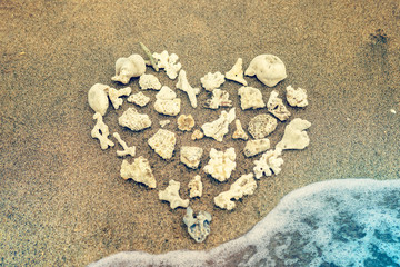 Fototapeta na wymiar Corals laid out in the shape of a heart on the beach. Vacation, relax, love.