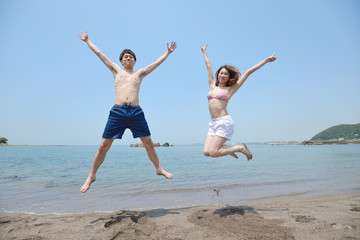 ビーチでジャンプするカップル