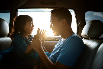 asian daughter with father in the car playing