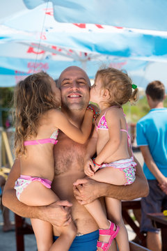 portrait of young happy father with daughters by the sea