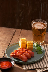 Beer and grilled sausages on wooden background