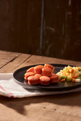 Sliced and fried sausage with salad seen from above close