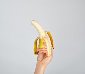 peeled fresh banana in female hand