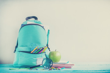 Full turquoise School Backpack with stationery on table. Concept back to school.