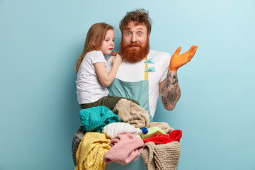 Puzzled ginger father confused, spreads hand as doesnt know how to calm crying sad daughter, busy...