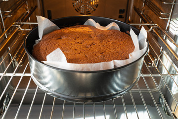 freshly baked cake in black for baking in an electric oven on a metal grill