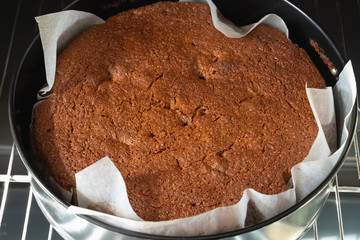 freshly baked cake in black for baking in an electric oven on a metal grill