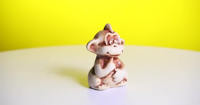 The Toy Brown Monkey Spins On A White Table. Yellow Background. Prores 4k