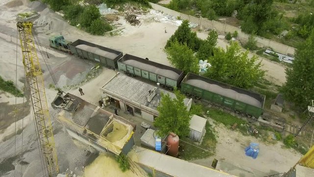 cargo train carrying industrial rubble at old concrete factory aerial shot