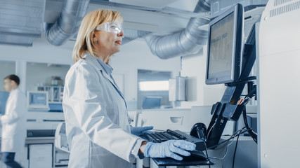 Female Scientists Programs Medical Equipment with Personal Computer. Team Of Professionals Working...