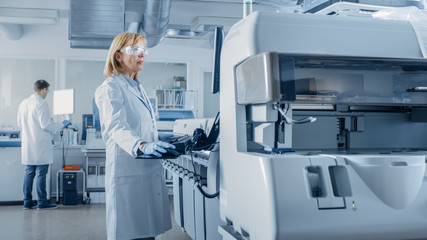 Female Scientists Programs Medical Equipment with Personal Computer. Team Of Professionals Working...