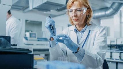 Female Research Scientist Uses Micro Pipette while Working with Test Tubes. People in Innovative...