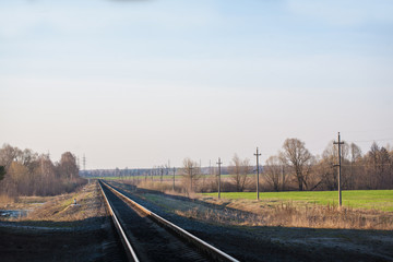 The railway at sunset, runs near an agricultural field, a spring landscape.
