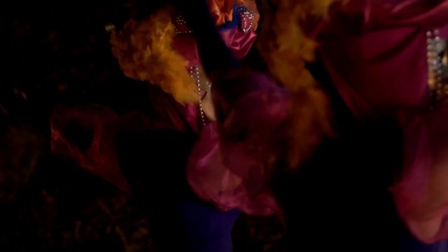 close-up of synchronously dancing girls in pink dresses, beads and gold masks. the girls on the headdresses of bright feathers.