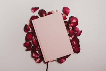 Pink diary on rose petals on a white background, toned, top view