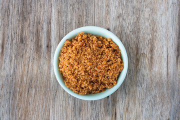 Sugar and chili in a cup on a wooden table.