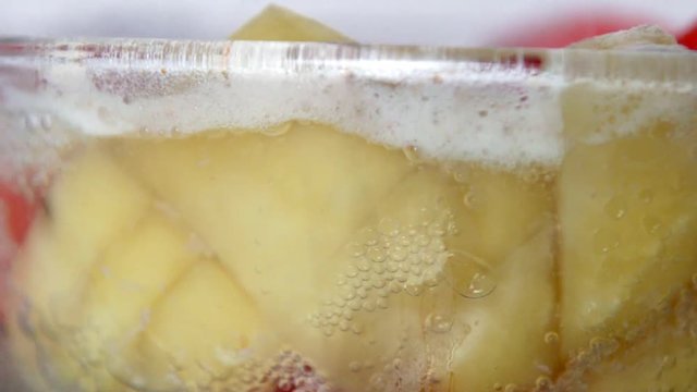 Slow motion of boiling soup broth with carrot and potato in glass pan