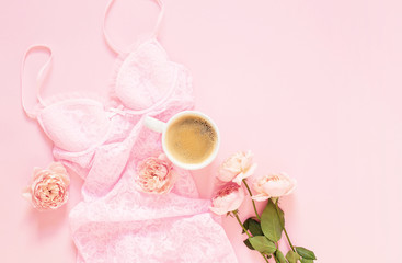 Composition of woman's lace nightie, flowers and black coffee on a light pink background. Morning concept. Flat Lay. Top View