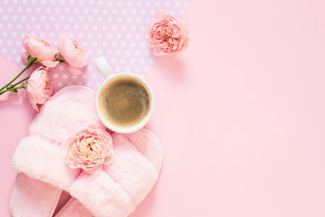 Composition of faux fur woman slippers, flowers and black coffee on a light pink background. Morning concept. Flat Lay. Top View