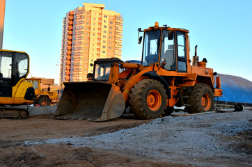 View of diesel wheel loader bulldozer with bucket on a construction site against a residential building