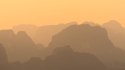 Landscape view of silhouettes and shapes of mountains and hills in asia in orange sunset time
