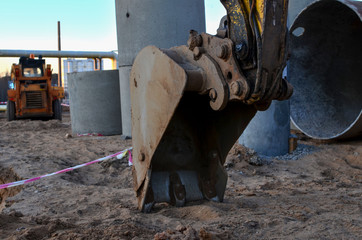 Iron excavator bucket in the sandy ground, earthworks concept
