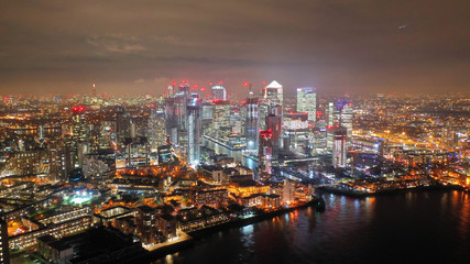 Aerial drone night shot from iconic Canary Wharf illuminated skyscrapers business and financial area, Docklands, Isle of Dogs, London, United Kingdom