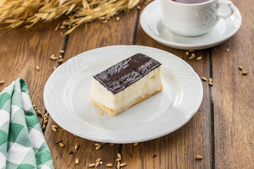 Vanilla souffle with dark chocolate glaze and cup of tea on wooden table