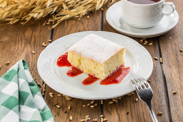 Homemade sponge cake with jam and cup of tea on wooden table
