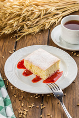 Homemade sponge cake with jam and cup of tea on wooden table