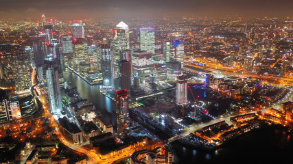 Aerial drone night shot from iconic Canary Wharf illuminated skyscrapers business and financial area, Docklands, Isle of Dogs, London, United Kingdom