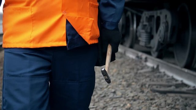 Worker in orange workwear walks near a railroad train car.