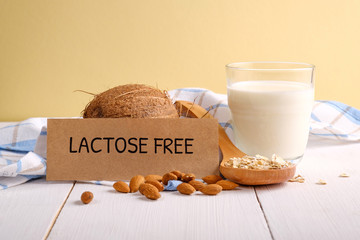 Lactose free milk. Glass of milk, almond nuts, oat flakes, coconut and piece of paper with text...
