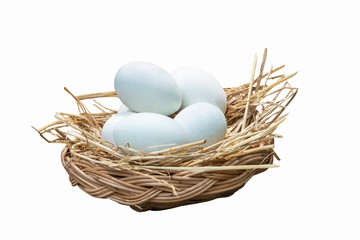 Many white shelled eggs in a wicker basket which is covered withe hay On the ground, to food and chicken farm concept